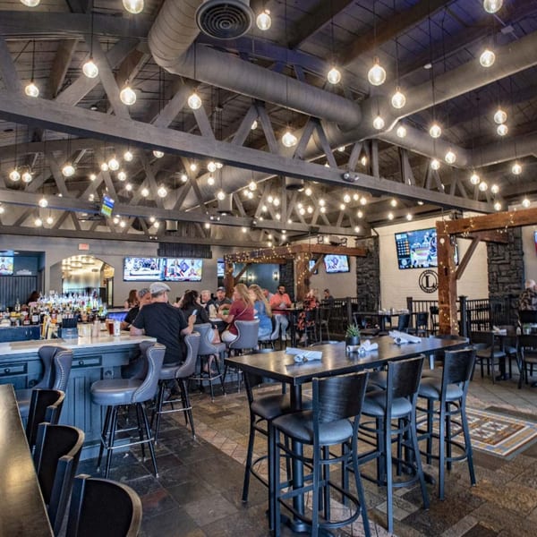 Label Kitchen + Bar's interior with patrons at the bar and high-top tables under string lights.