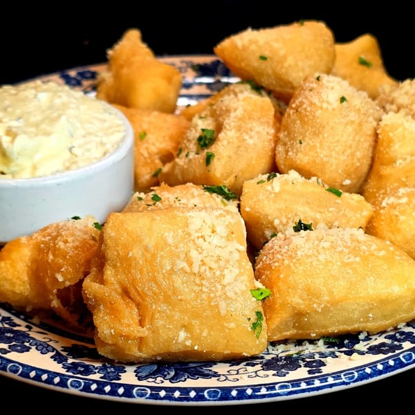 Golden fried dough bites, sprinkled with parmesan and parsley, served with a creamy dip.